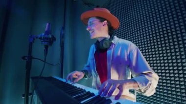 A man is playing the piano and singing in the recording booth. 4K
