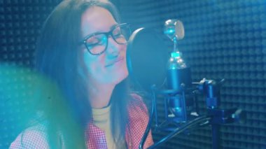 A beautiful woman is singing into a studio microphone. 4K