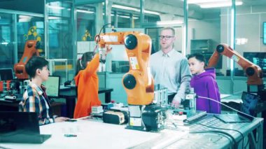 Male tutor is explaining robotics to a group of children. 4K