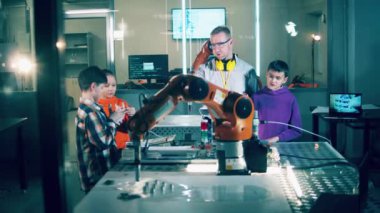A group of kids are studying robots with their tutor. 4K