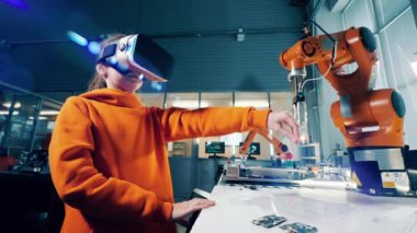 Bir kız robot koluyla çalışmak için VR gözlük kullanıyor. 4K