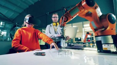 A tutor is monitoring a girl using VR-glasses to work with a robot. 4K