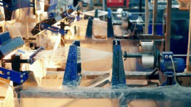 Industrial machines are covering glass fibers with glue. 4K