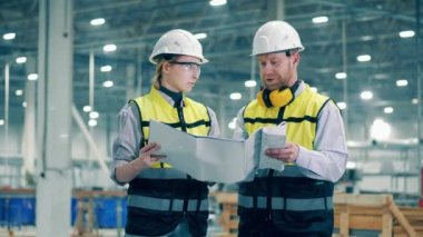 İki mühendis fabrika belgelerini tartışıyorlar. 4K