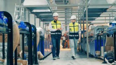 Two coworkers are talking while going through the factory. 4K