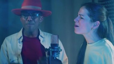 A man and a woman are singing as a duo while being recorded. 4K