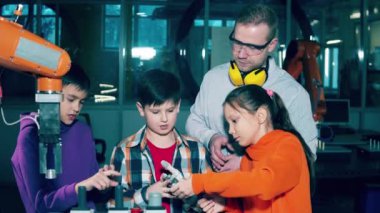 Çocuklar ve bir robot uzmanı biyonik parçaları inceliyor. 4K