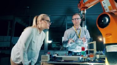 İki robot uzmanı hareket halindeki bir mekanizmayı gözlemliyor. 4K