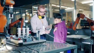 Erkek uzman bir çocuğa biyonik bir el gösteriyor. 4K