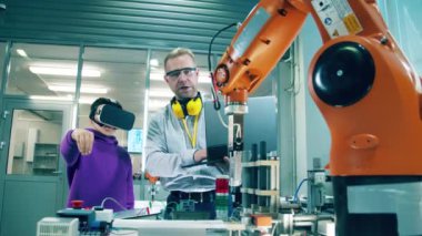 Eğitmen, VR 'da bir robotu yönetmesine yardım ediyor. 4K