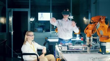 Engelli teknisyen, iş arkadaşını VR gözlük kullanarak gözlemliyor. 4K