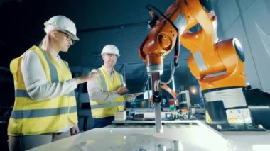 Kask takmış robot mühendisleri robotları inceliyor. 4K