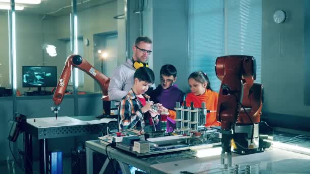 孩子们和他们的导师正在看着一只机器人的手 — 图库视频影像