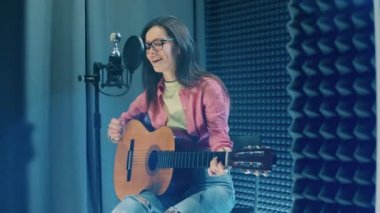 Bayan sanatçı kayıt kabininde gitar çalıyor. 4K