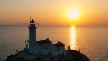 Gün batımının arka planında deniz feneri. 4K