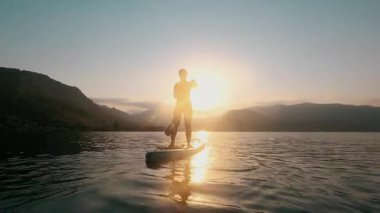 Sudaki kadın silueti, yemek masası, ağır çekimde sörf tahtası.