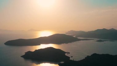 Gün batımı sakin sularda güzel bir şekilde adaları aydınlatıyor, gezginler ve doğa severler için mükemmel bir sahne yaratıyor.