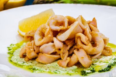 Kızarmış kalamar halkaları ya da soslu kalamar ve beyaz tabakta limon..