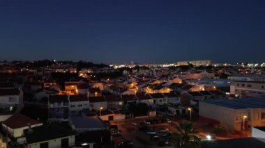Gece kasabasının insansız hava aracı panoraması. Evlerin ve bahçelerin pencerelerinde ışık.