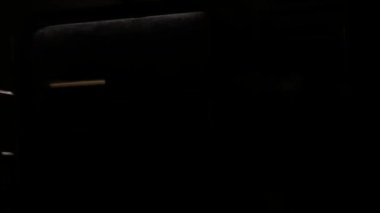 Tren karanlık bir tünelden geçiyor. Tünelin parlak beyaz ışıkları pencerenin dışında yüksek hızda yanıp sönüyor..