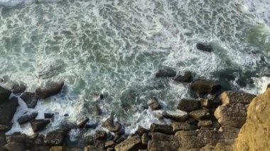 Ağır çekimde okyanus dalgaları kayalık oluşumlara ve taşlara çarpar ve hareketli denizin gücünü ve güzelliğini vurgular..
