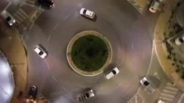 İnsansız hava aracı kavşağın üzerinde hızla yükselir ve döner, arabaların dinamik hareketlerini yakalar, daireleri sorunsuzca dolaşır, farlar ve sokak lambalarıyla aydınlatır..