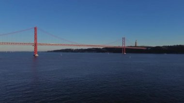 25 Nisan 'da Lizbon, Portekiz' de güneş batarken insansız hava aracı görüntüsü. Ponte 25 de Abril. Tejo Nehri üzerindeki asma köprü.
