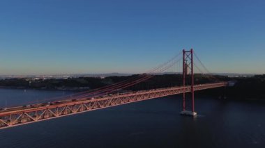 25 Nisan 'da Lizbon, Portekiz' de güneş batarken insansız hava aracı görüntüsü. Ponte 25 de Abril. Tejo Nehri üzerindeki asma köprü.
