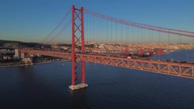 25 Nisan 'da Lizbon, Portekiz' de güneş batarken insansız hava aracı görüntüsü. Ponte 25 de Abril. Tejo Nehri üzerindeki asma köprü.