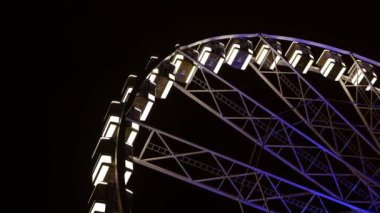 Parkta gece vakti renkli beyaz ve mavi parlayan dönme dolap aydınlandı..