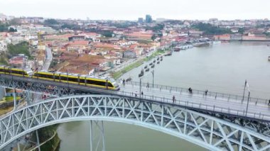 A drone rises above the Ponte de D. Luis in Porto, Portugal, flying over the Douro River and following a metro train as it crosses the bridge. 15.01.2024