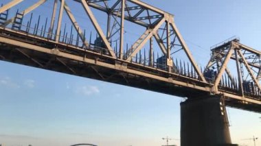 Freight train moving on a railway bridge over a river. Under bridge view. Low angle. 