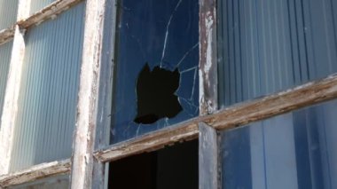 Eski, ahşap bir çerçevenin kırık penceresi. Bardaktaki delik. Eski moda pencere. Vandalizm.