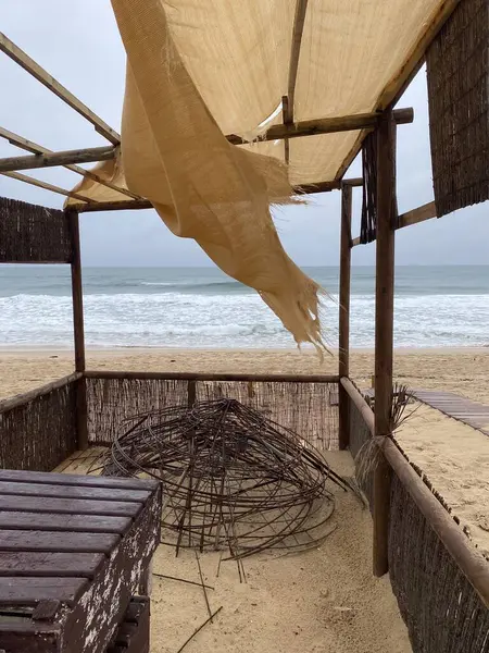 Bej rengi paçavralar rüzgarda dalgalanıyor, bulutlu bir gökyüzünün altında yumuşak okyanus dalgaları olan boş bir kumsal. Sönük renkler, aşınmış kumaş, melankolik, nostaljik atmosfer..