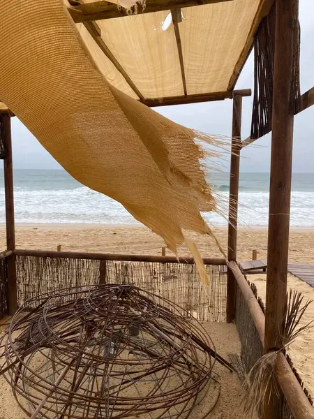Bej rengi paçavralar rüzgarda dalgalanıyor, bulutlu bir gökyüzünün altında yumuşak okyanus dalgaları olan boş bir kumsal. Sönük renkler, aşınmış kumaş, melankolik, nostaljik atmosfer..