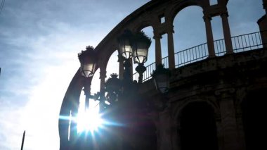 Valencia, İspanya 'da romantik bir sabah manzarası. Valencia Katedrali 'nin tarihi kemerleriyle yükselen güneşe karşı siluetli klasik bir sokak lambası. Avrupa 'da huzurlu şehir sabahları.