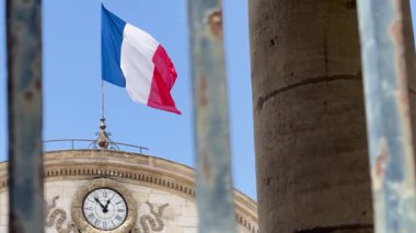 Fransız bayrağı, yıpranmış taş sütunlar ve demir bir çitin ardında sallanıyor. Fransa 'nın mirasının ve ulusal gururunun sembolik bir görüntüsü..