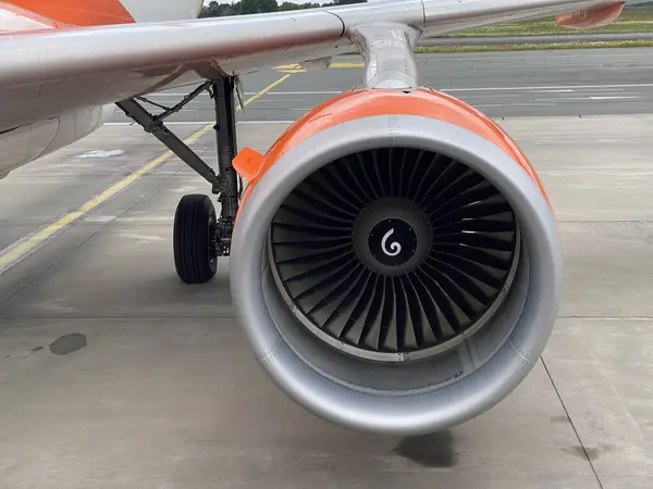 Jet motorlu türbin ve iniş takımlarını park etmiş bir uçağa yakın plan. Havaalanı pistinde modern havacılık teknolojisi.