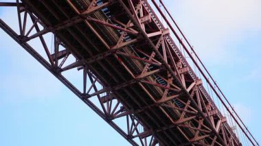 Portekiz, Lizbon 'daki 25 de Abril Köprüsü' nün düşük açılı yakın plan görüntüleri, kırmızı çelik yapının endüstriyel kentsel ruh halini, estetiğini ve kalın geometrik yapısını vurguluyor.. 