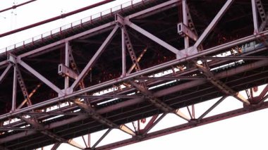 Lizbon, Portekiz 3 Haziran 2025: 25 de Abril Köprüsü 'nün yakınından geçen bir tren, günbatımında endüstriyel bir şehir havasında ele geçirildi..