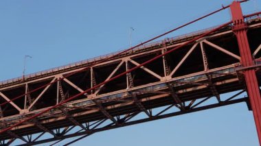 Lizbon, Portekiz 3 Haziran 2025: 25 de Abril Köprüsü 'nün yakınından geçen bir tren, günbatımında endüstriyel bir şehir havasında ele geçirildi..