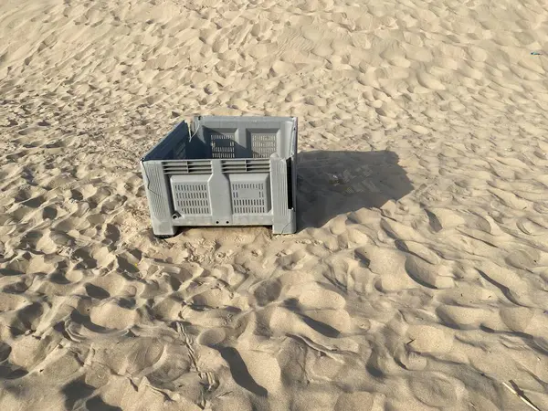 Kumsalda terk edilmiş gri balık plastik sandığı. Gölgeler, güneş. 