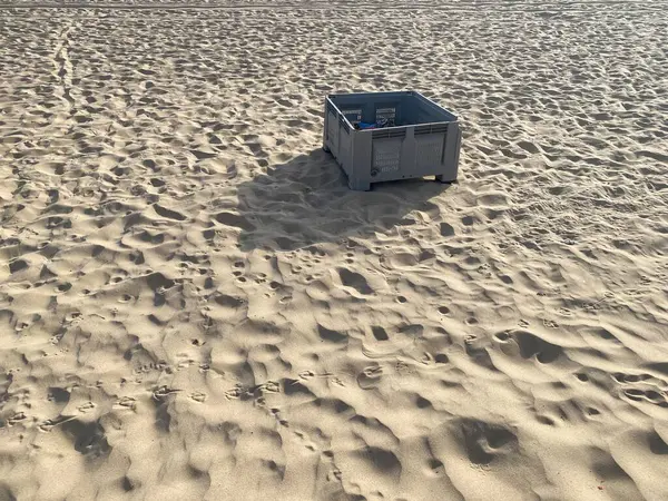 Kumsalda terk edilmiş gri balık plastik sandığı. Gölgeler, güneş. 