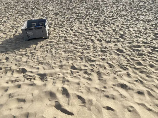 Kumsalda terk edilmiş gri balık plastik sandığı. Gölgeler, güneş. 