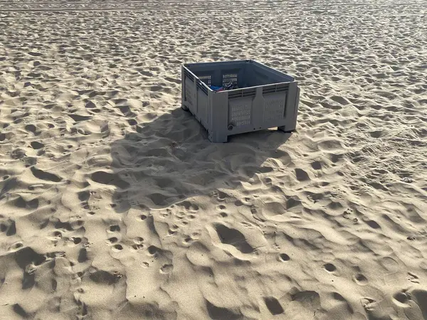Kumsalda terk edilmiş gri balık plastik sandığı. Gölgeler, güneş. 