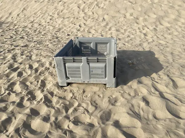 Kumsalda terk edilmiş gri balık plastik sandığı. Gölgeler, güneş. 
