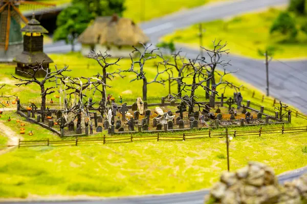 Mezar taşları, hayaletler ve balkabaklarıyla ürkütücü bir minyatür mezarlık diyorama ortamında tuhaf bir cadılar bayramı sahnesi yaratıyor.