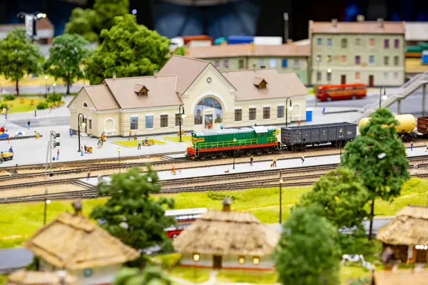 Minyatür kasabada, platformda bekleyen yolcularla birlikte yeşil tren geliyor.