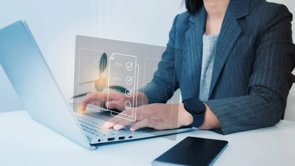 Businesswoman using a laptop and touching on virtual screen contact questionnaire with checkboxes, filling survey form online, answering questions of the test