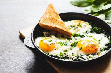 Dökme demir tavada yeşil Shakshuka. Ispanaklı yumurta ve kızarmış tost. sağlıklı besleyici kahvaltı,